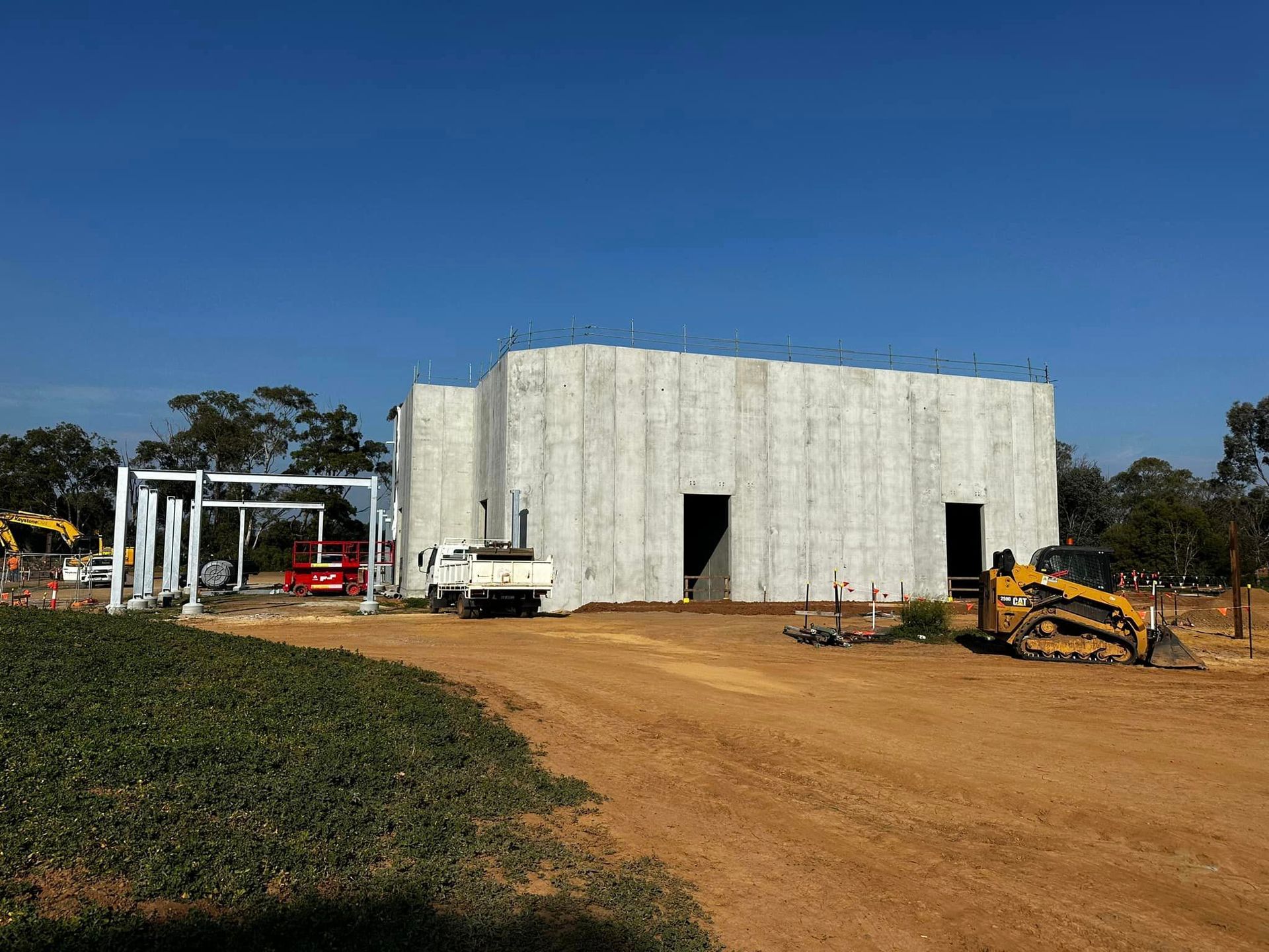 A large concrete building is being built in a dirt field.