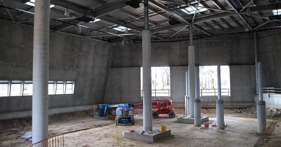 The inside of a building under construction with columns and windows.
