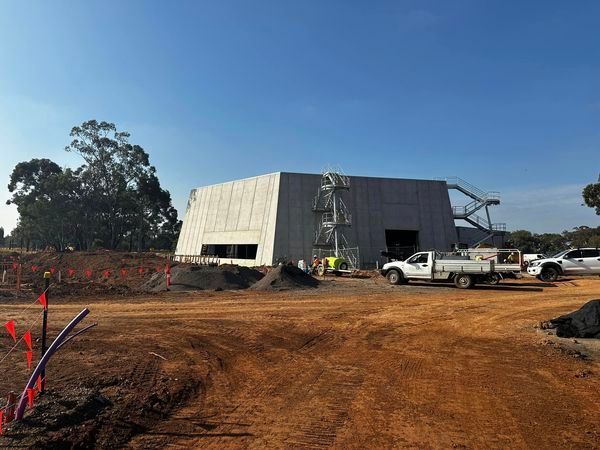 A white truck is parked in front of a building under construction.