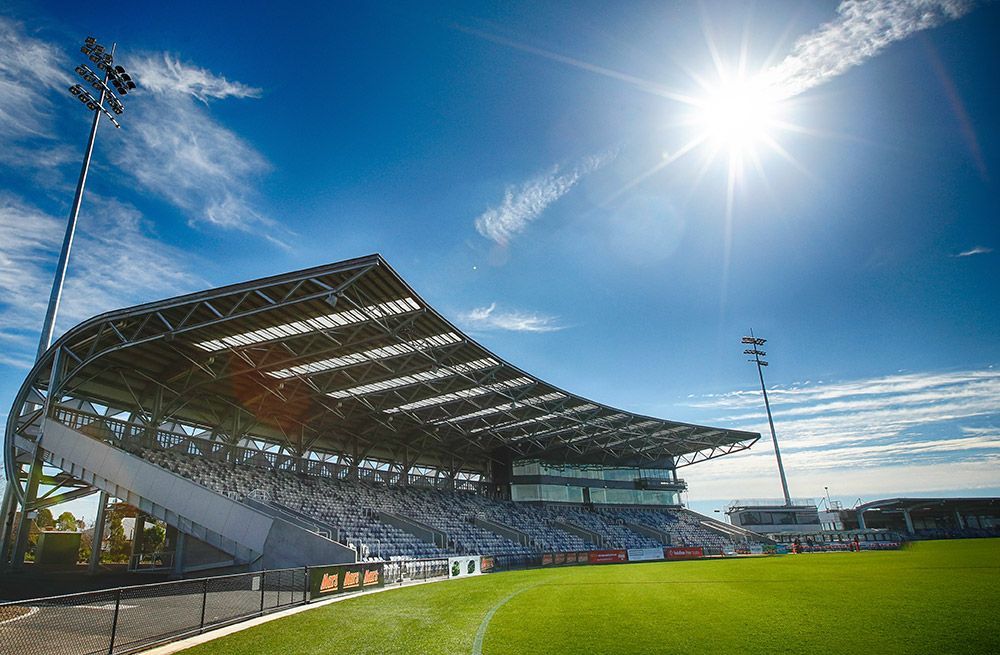 The sun is shining brightly over a soccer stadium on a sunny day.