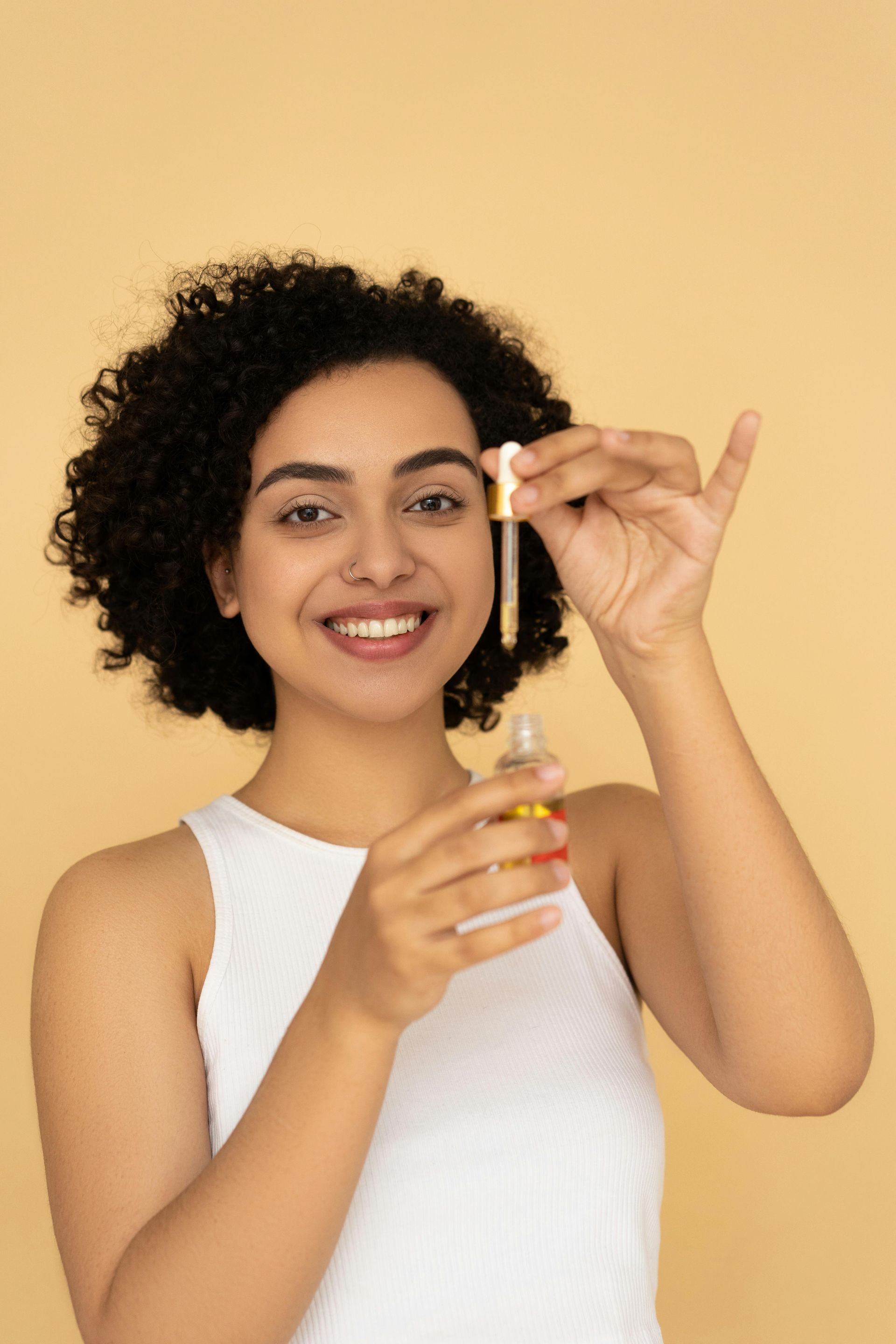 A woman is applying a serum to her face with a pipette.