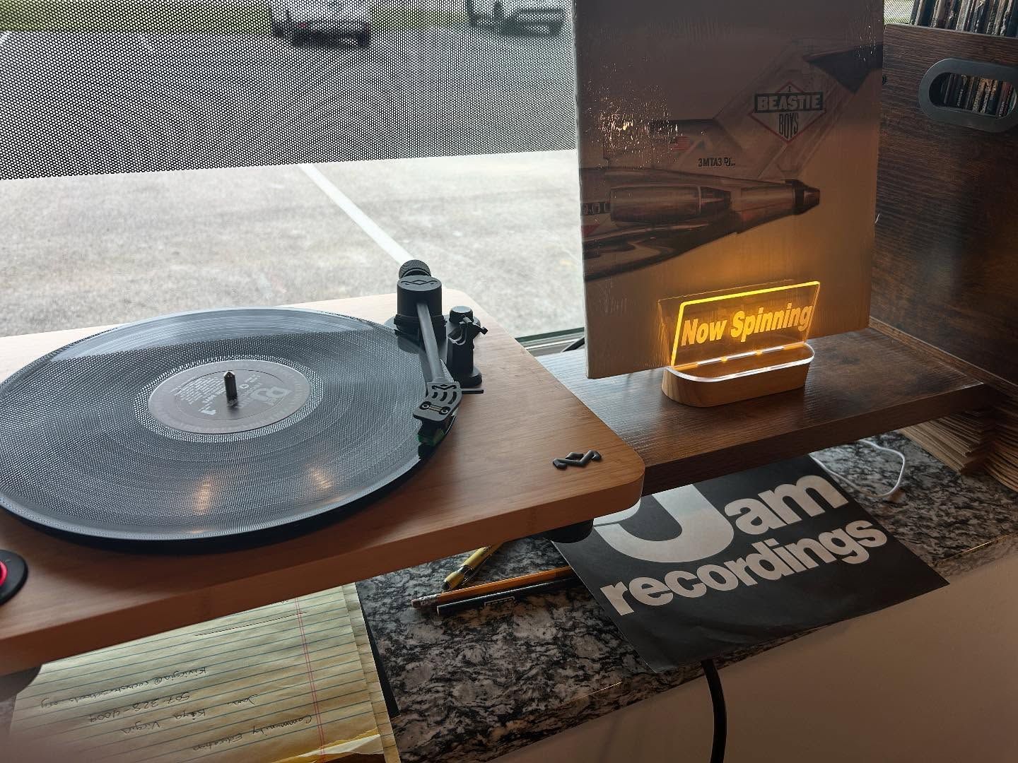 A record player with a vinyl record. A neon sign says 
