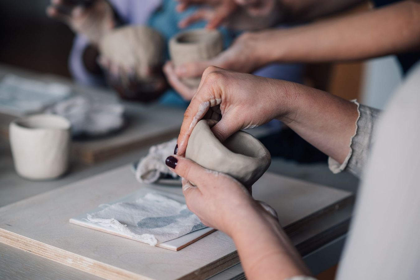 Person shaping a clay bowl with their hands at a pottery class.