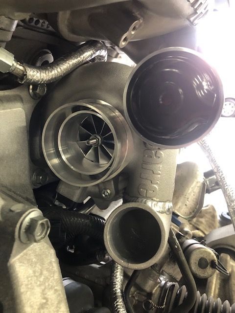 Close-up of a turbocharger with exposed impeller blades and intake, mounted on an engine block. | SB Automotive
