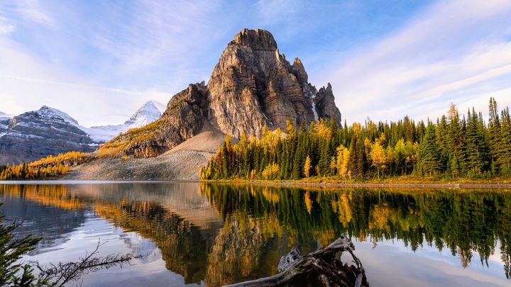 A mountain is reflected in a lake surrounded by trees.