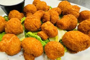 Fried mushrooms on a bed of lettuce, with white dipping sauce.