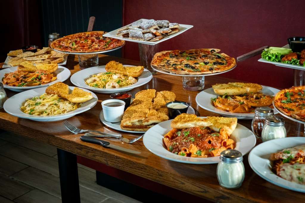 A table filled with various Italian dishes including pizza, pasta, and appetizers.