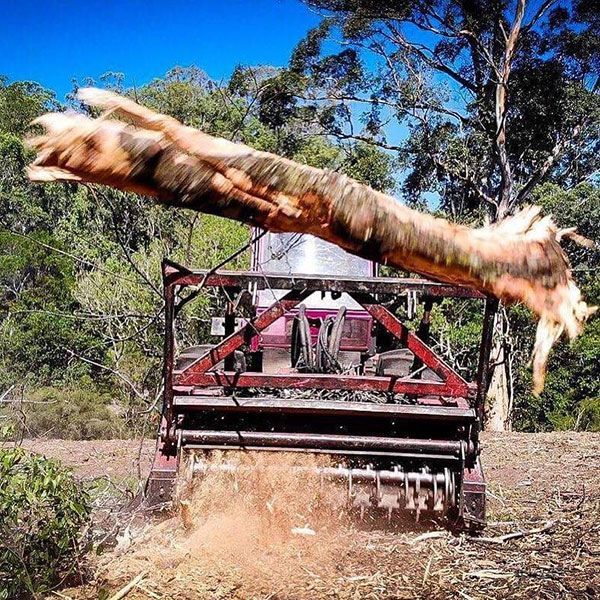 A large tree stump is being lifted by a tractor