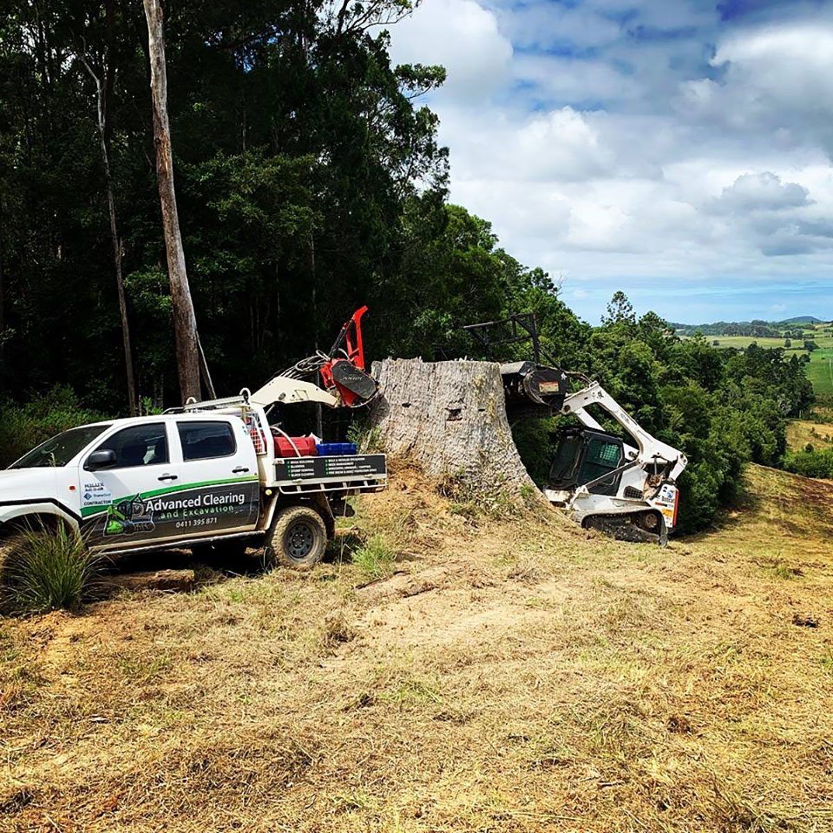 A truck is parked in a field next to a large tree stump.