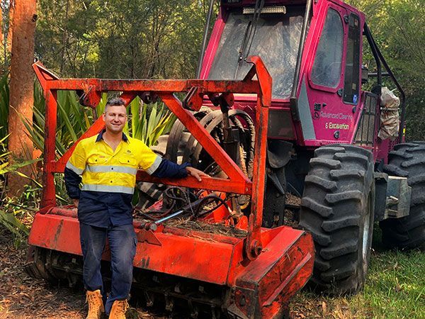 A man is standing in front of a large red tractor.
