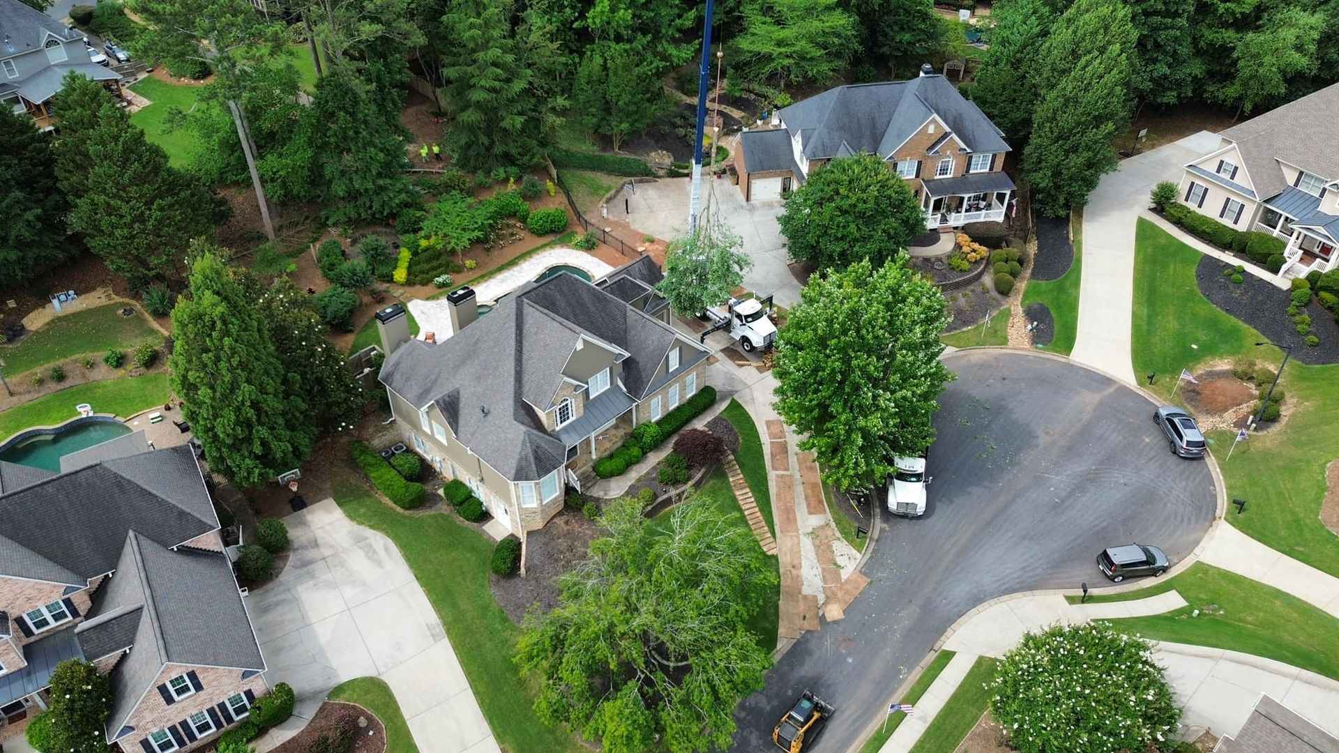 Aerial view of upscale homes with manicured lawns, trees, and a curved street.