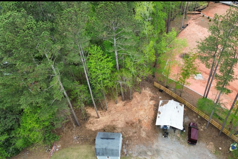 Overhead view of trees, a building, and a structure with a red roof.