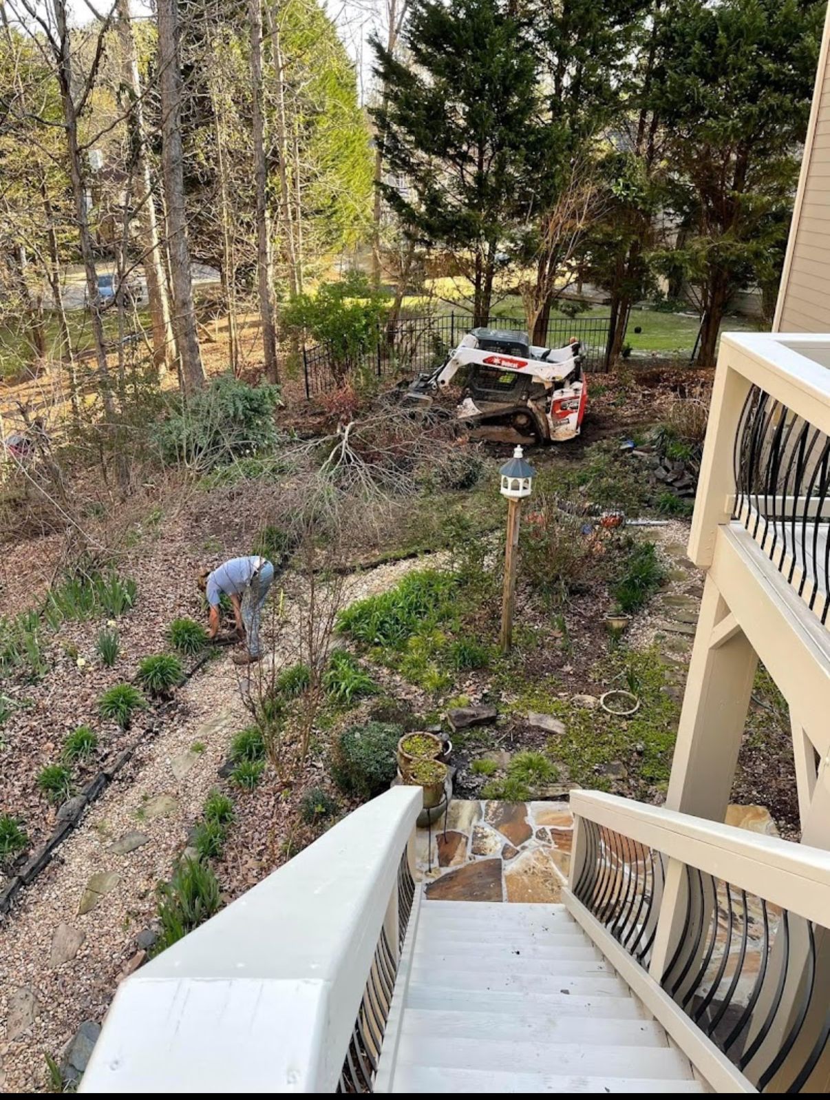 A person gardening in a yard. A car is in the background. A staircase is in the foreground.