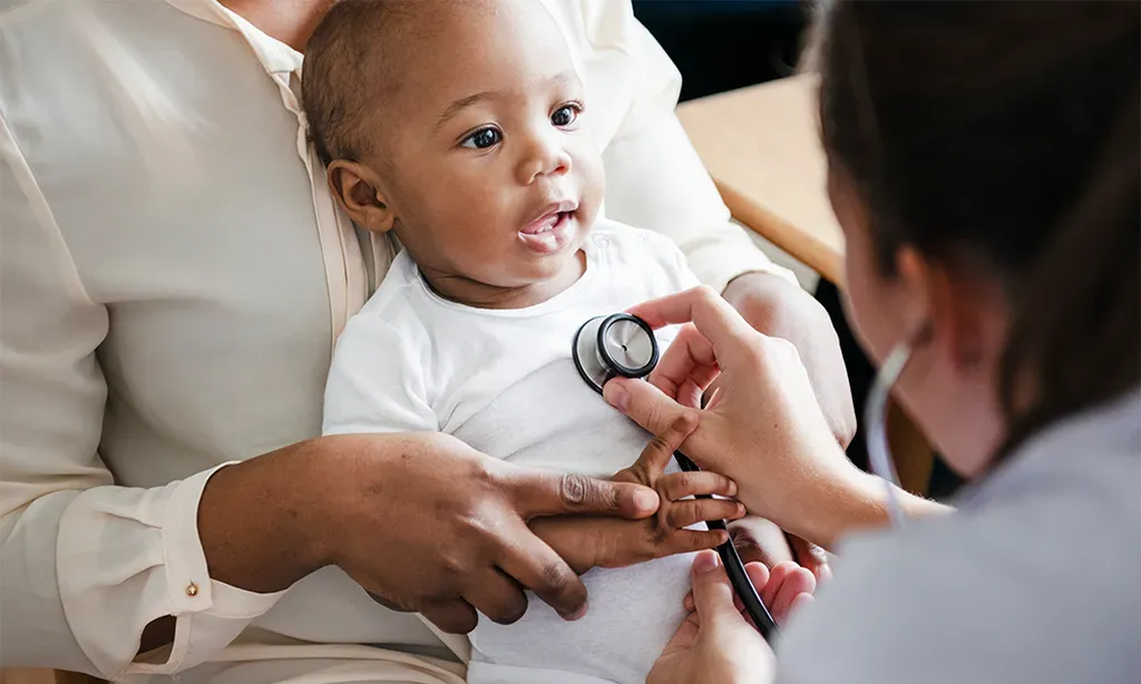 A baby is being examined by a doctor with a stethoscope.