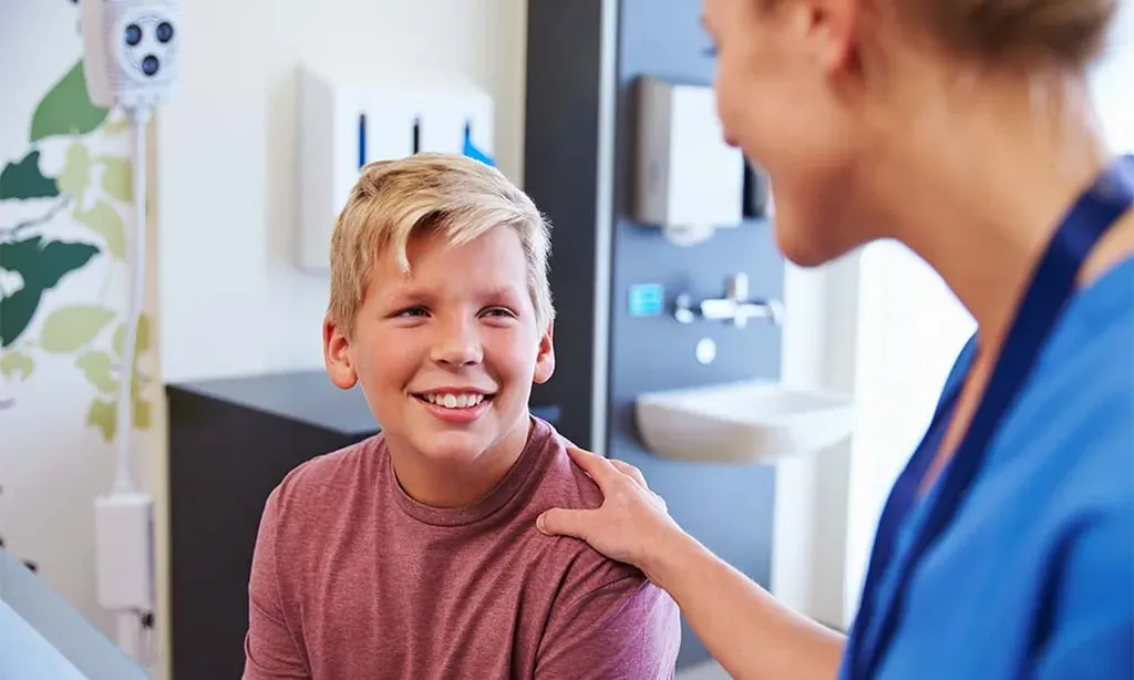 A nurse is talking to a young boy in a hospital room.