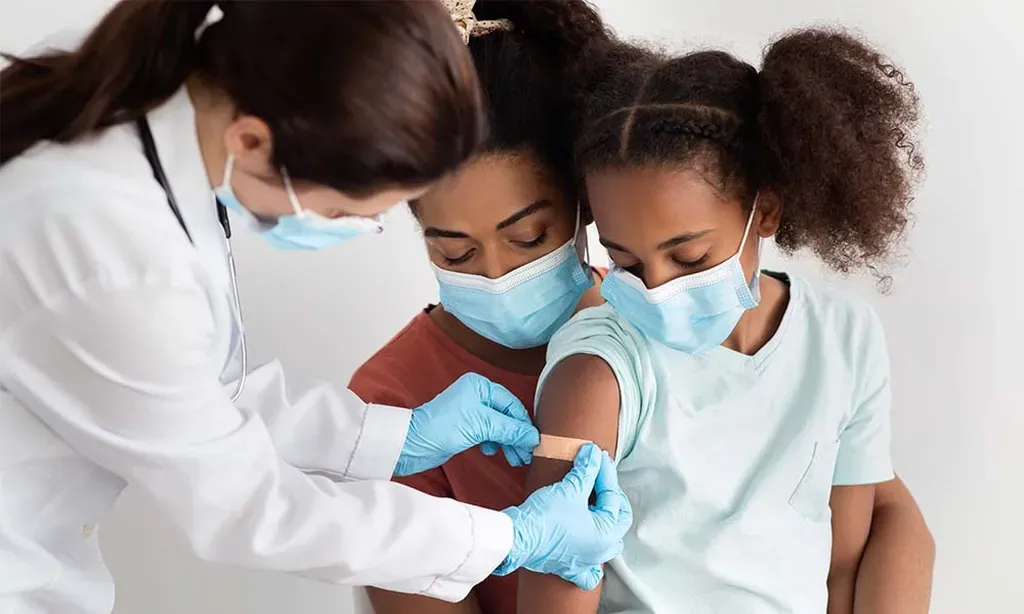 A woman and two children are getting a vaccine from a doctor.