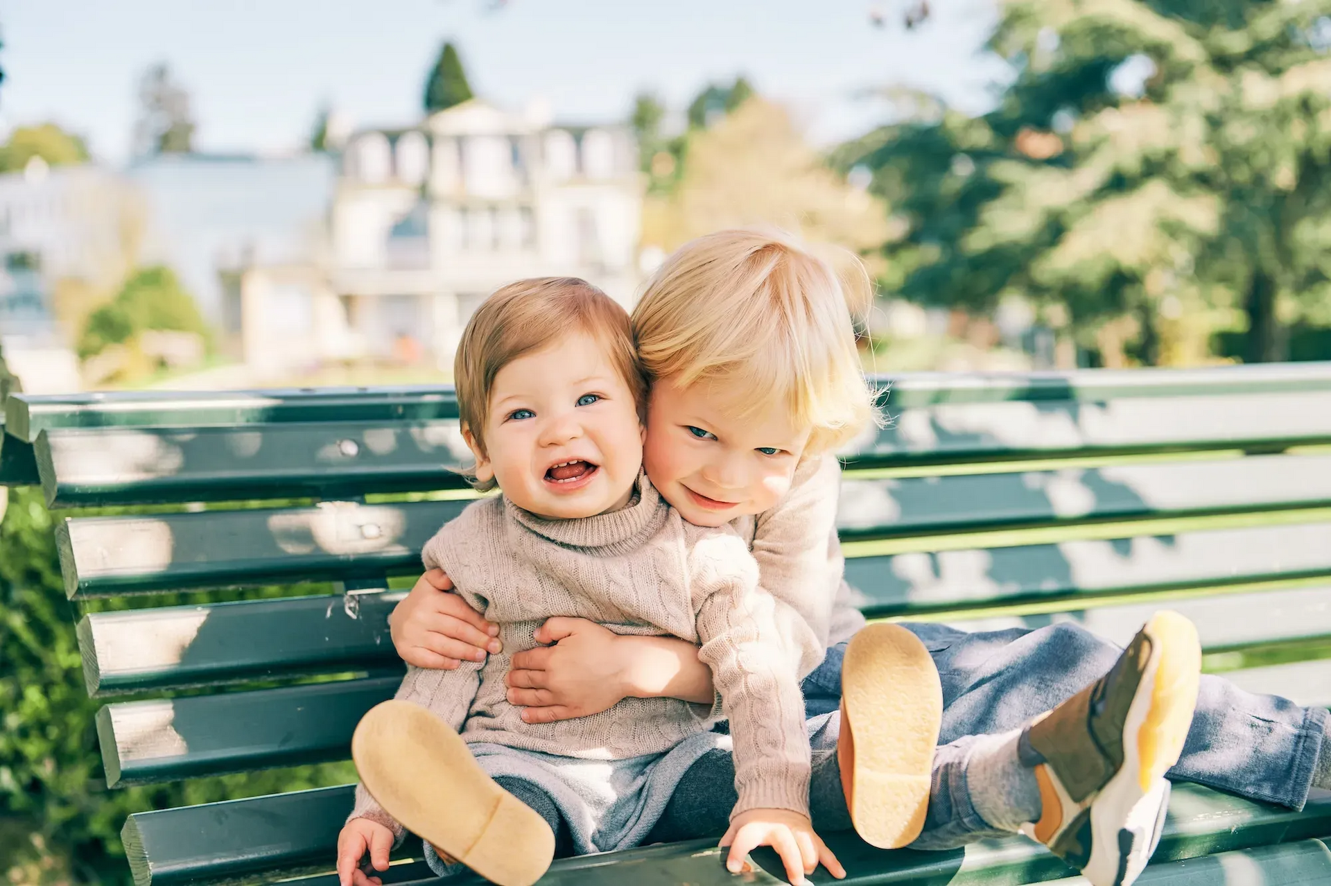 Two little girls are sitting on a park bench.