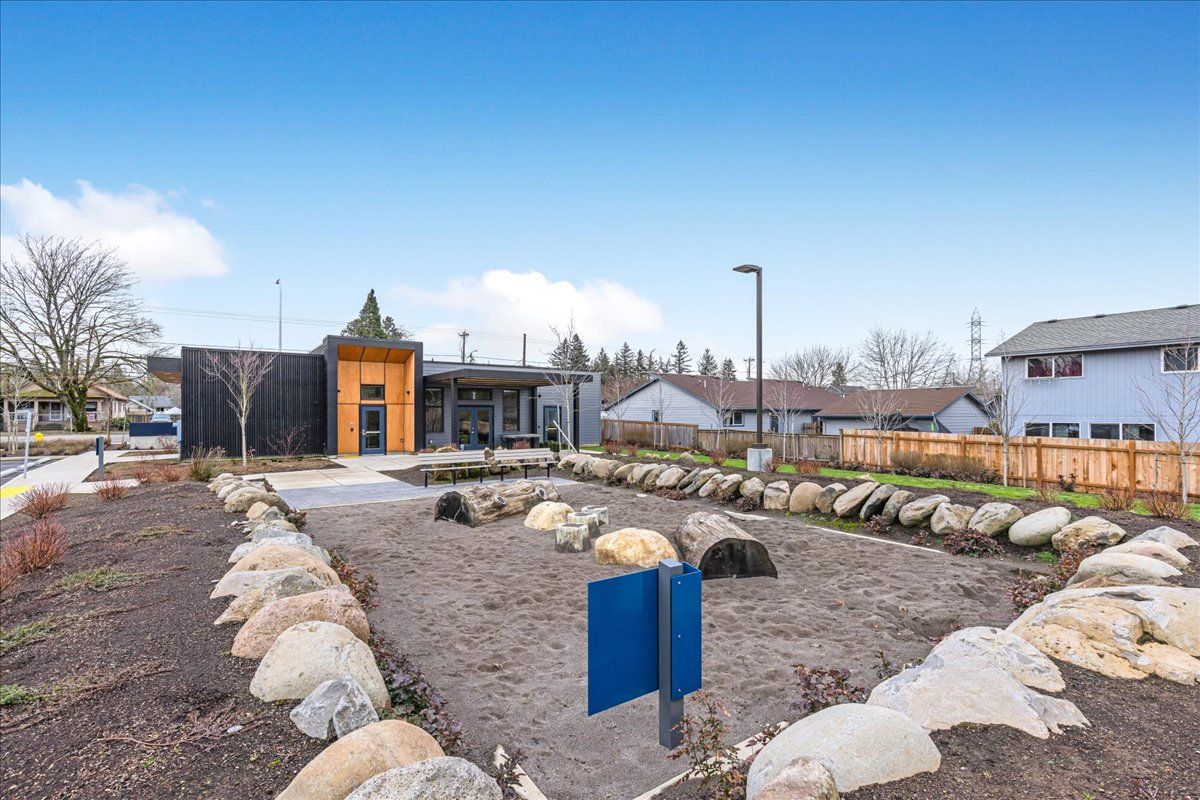 a blue sign is in the middle of a rocky area in front of a house .