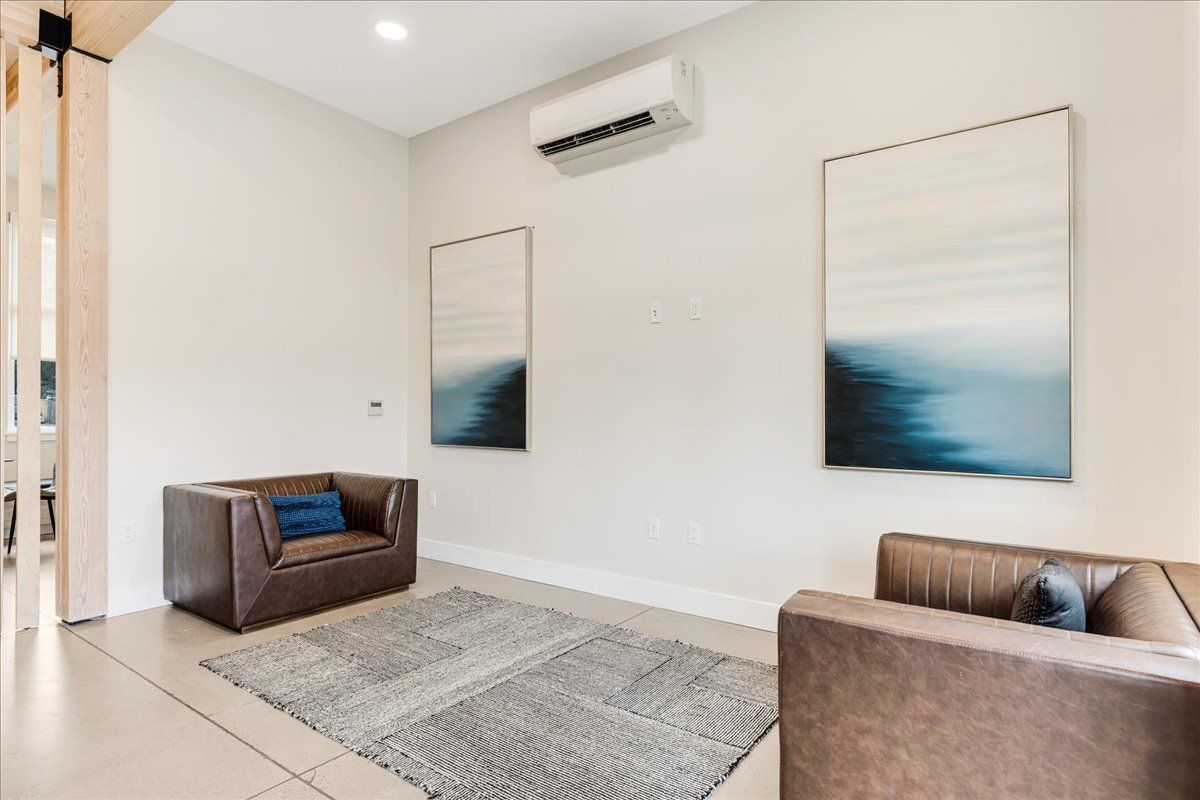 a living room with two chairs and two paintings on the wall .