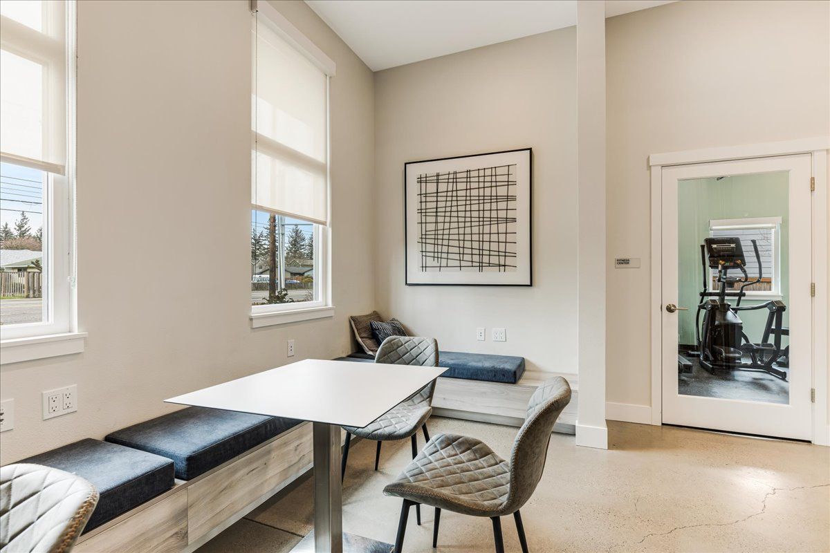 a room with a table and chairs in it and a gym in the background .