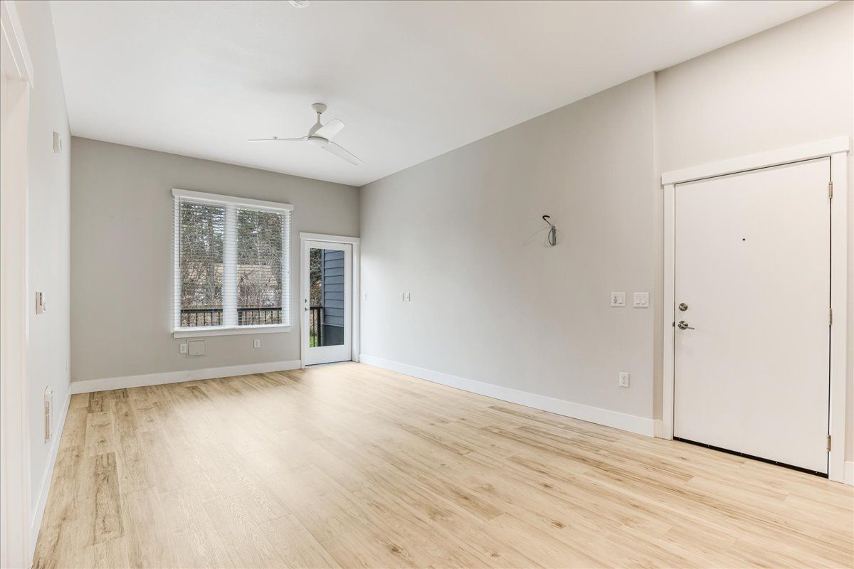 an empty living room with hardwood floors and a ceiling fan .