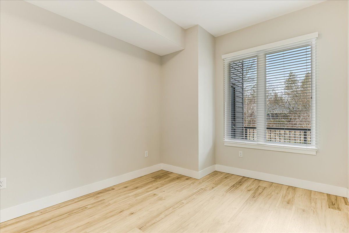 an empty room with hardwood floors and a large window .
