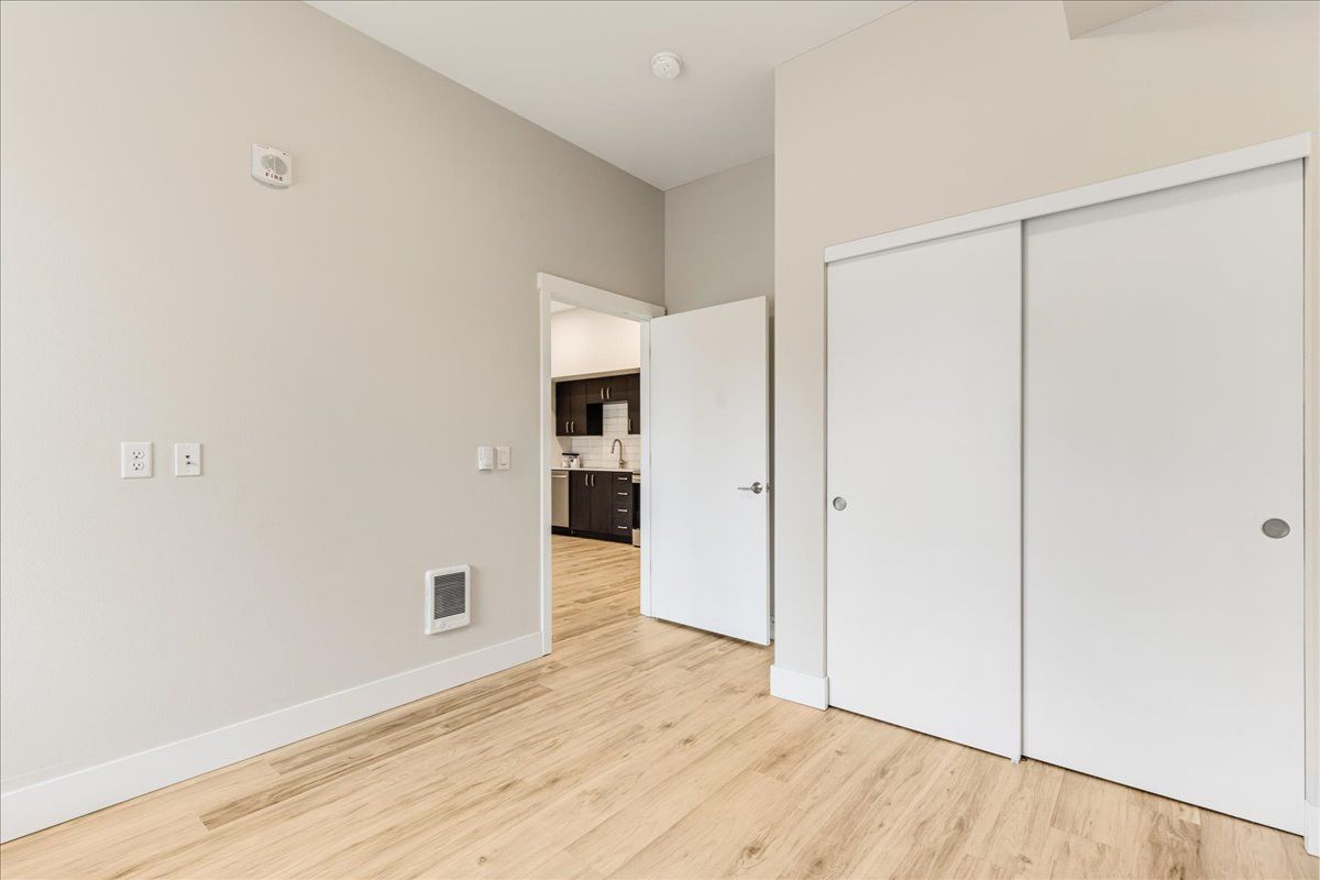 an empty bedroom with hardwood floors and white walls .