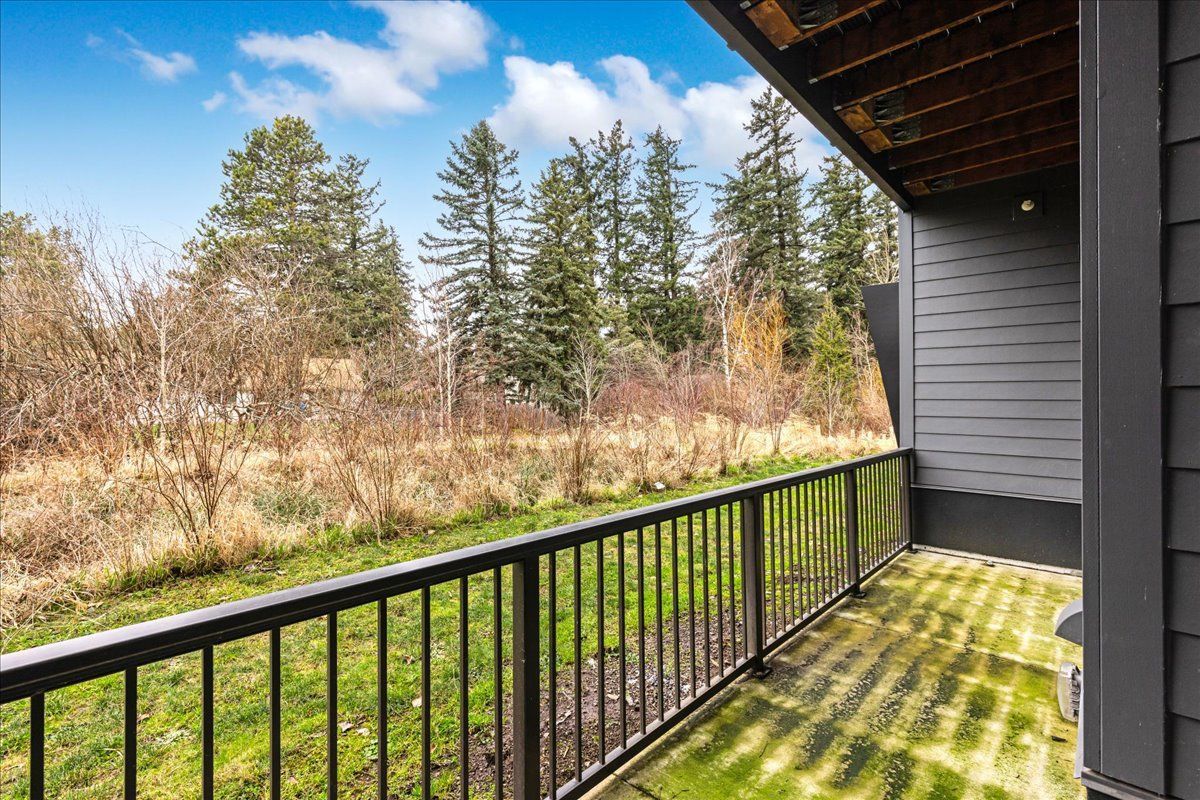 a balcony with a metal railing overlooking a grassy field .