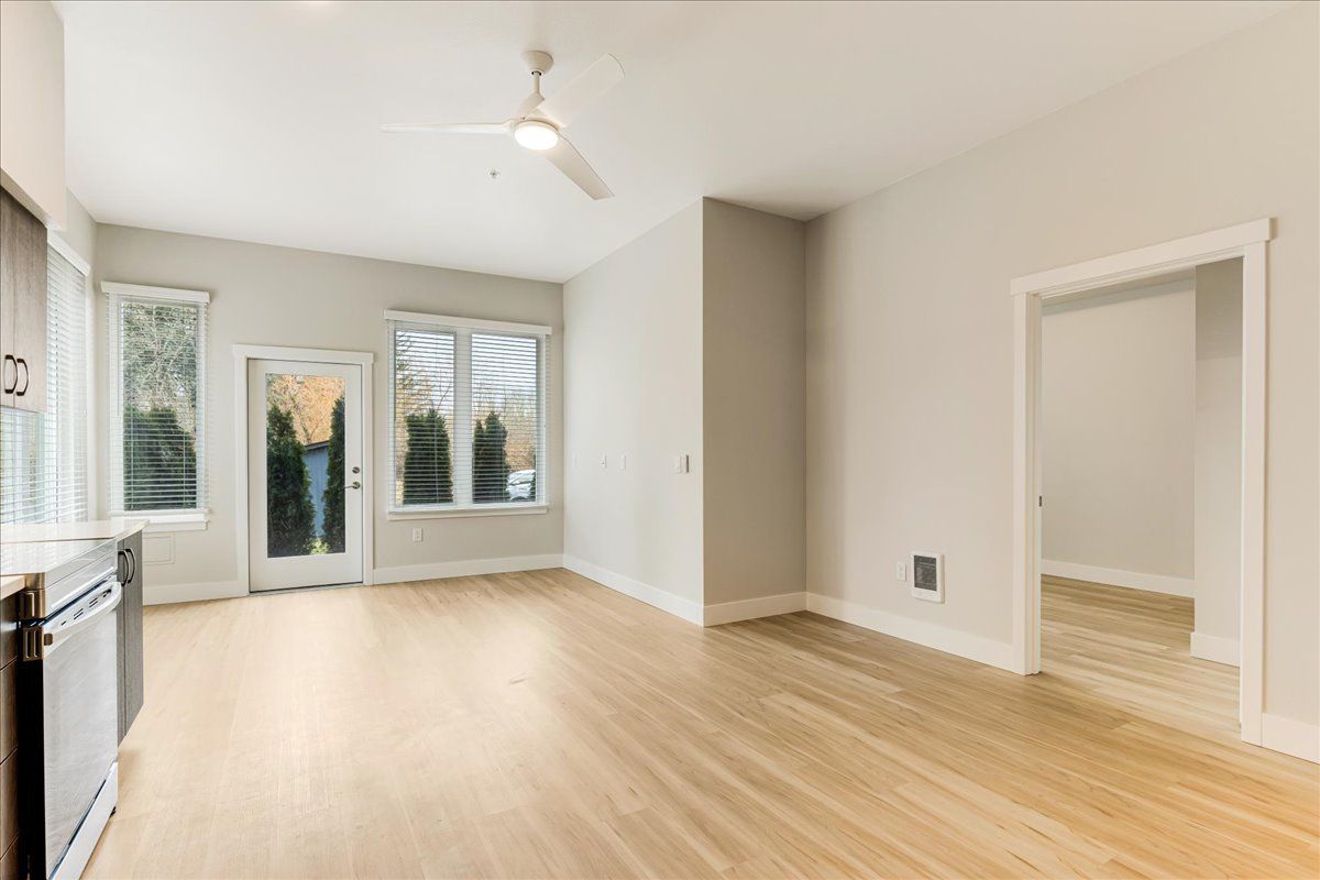 an empty living room with hardwood floors and a ceiling fan .
