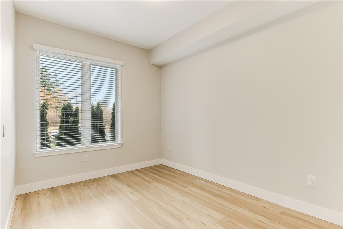 an empty room with hardwood floors and two windows .