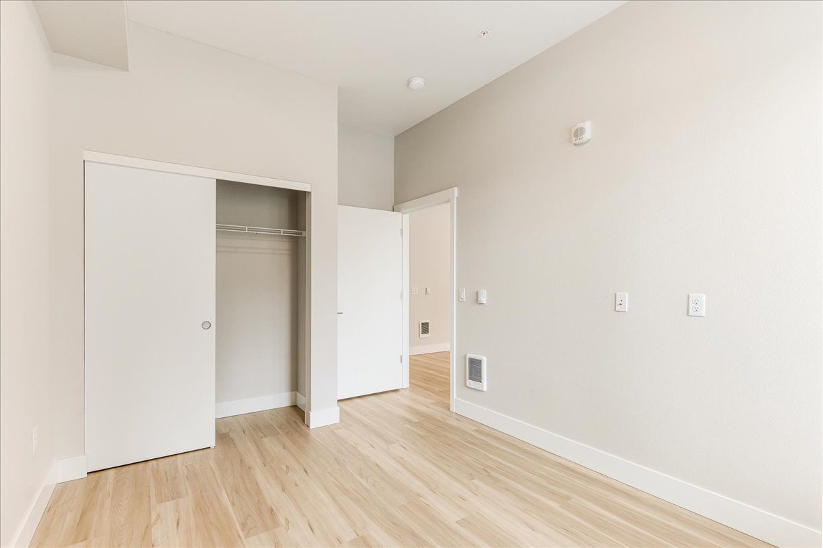 an empty bedroom with hardwood floors and a closet .