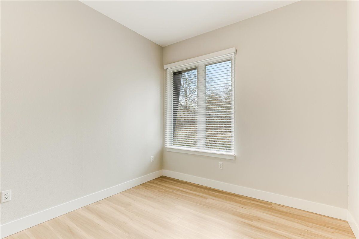 an empty room with a window and blinds .