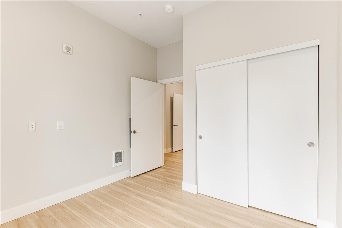 an empty bedroom with white walls and hardwood floors .
