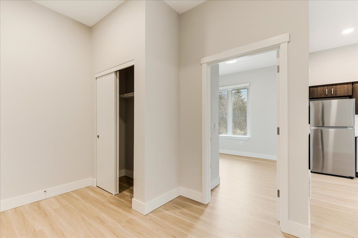 an empty room with hardwood floors and a stainless steel refrigerator .