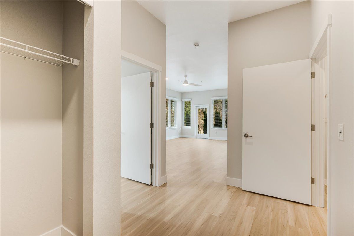 a hallway in a house with hardwood floors and white doors leading to a living room .