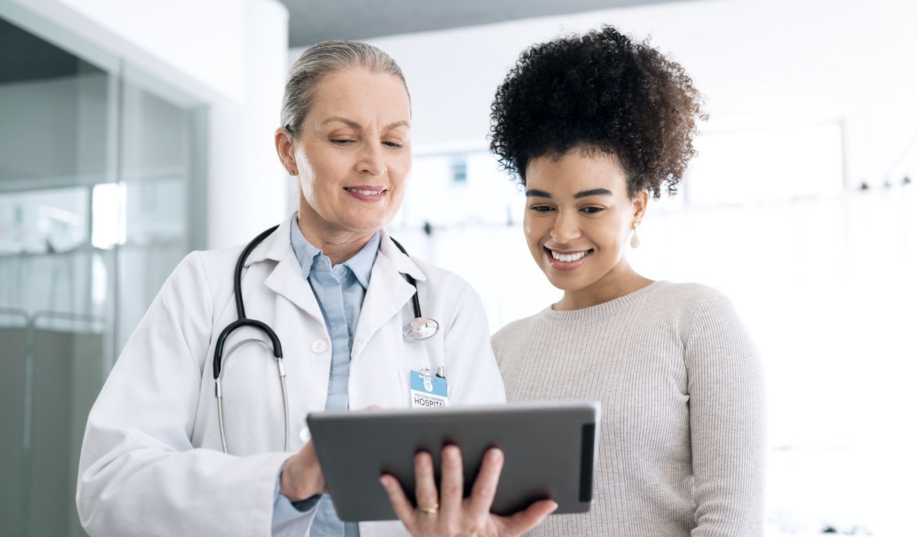 Thermographic Imaging: Confident female doctor shows test results on digital tablet to smiling woman
