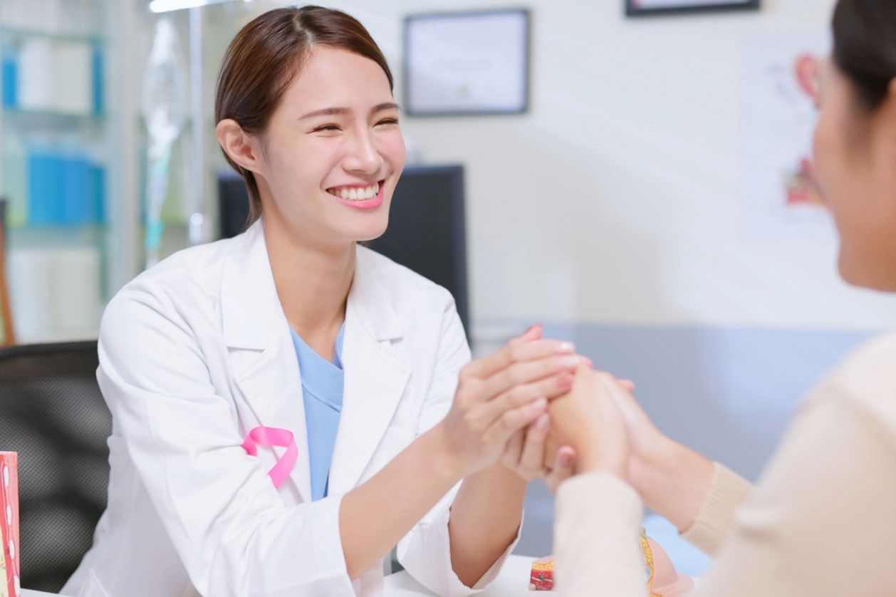 Breast thermography: A female doctor holding the hands of her female patient during her appointment.