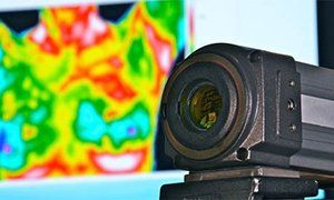 A close up of a camera with a thermal image in the background.