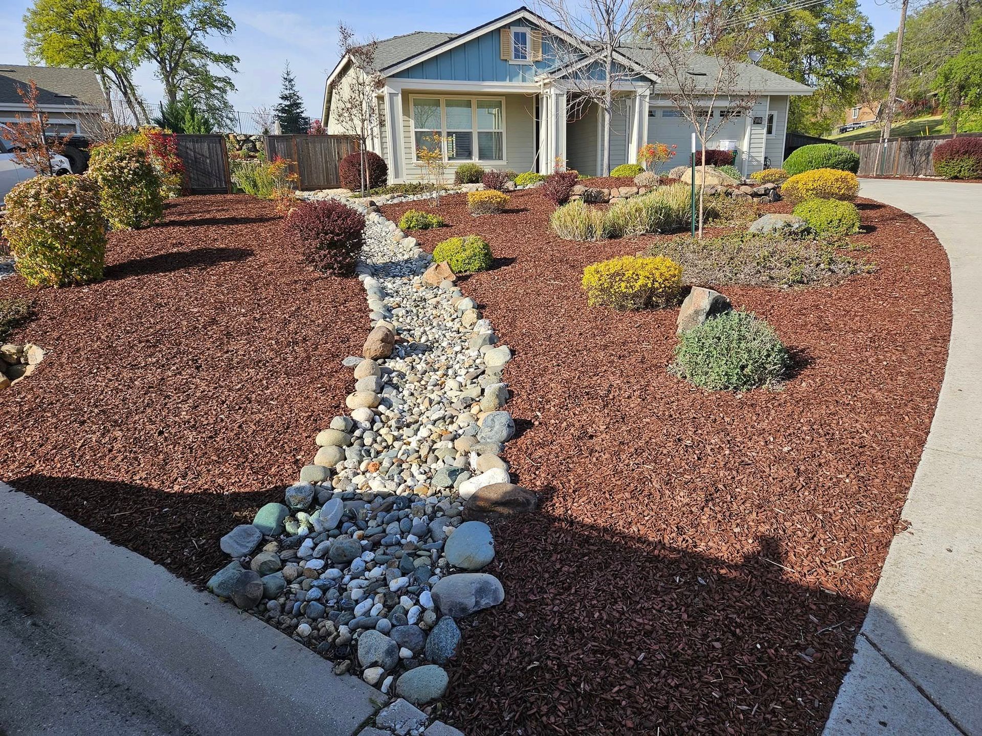 A house with a walkway leading to it surrounded by mulch and rocks.