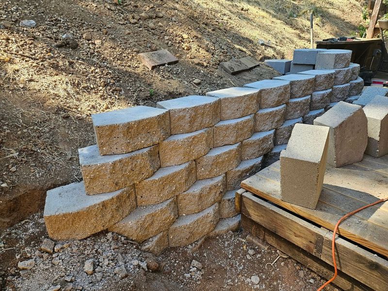 A brick wall is being built on top of a dirt hill.