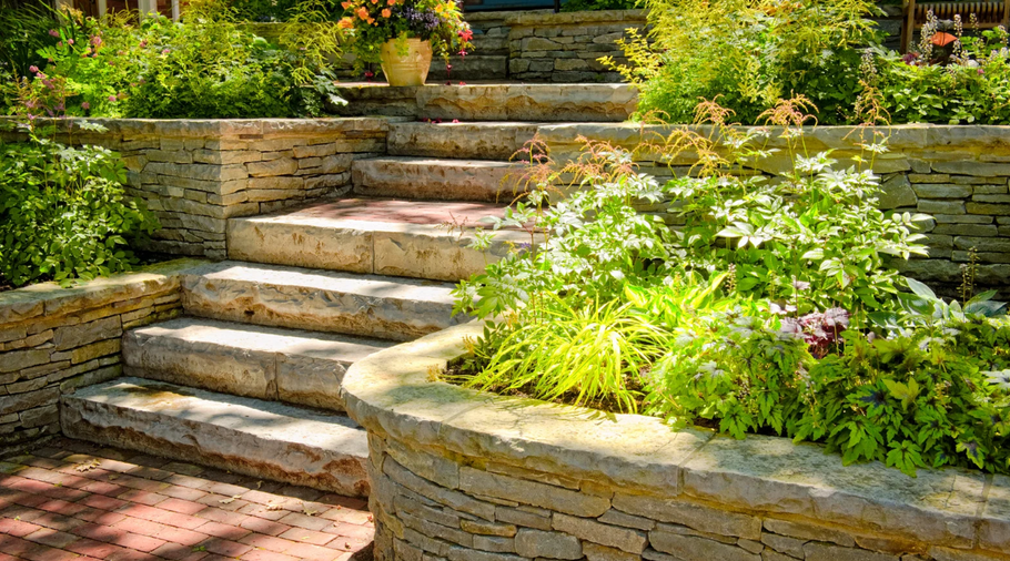 A stone staircase leading up to a house surrounded by plants and flowers.
