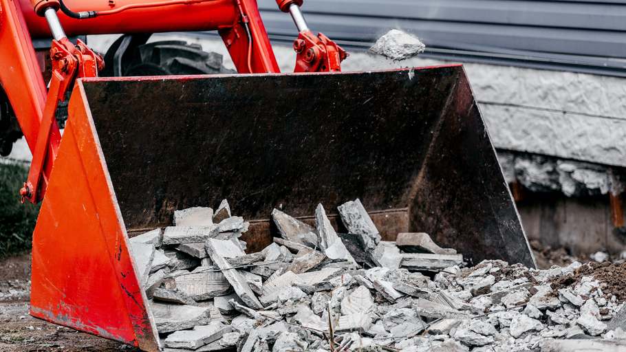 A bulldozer is scooping up concrete from the ground.