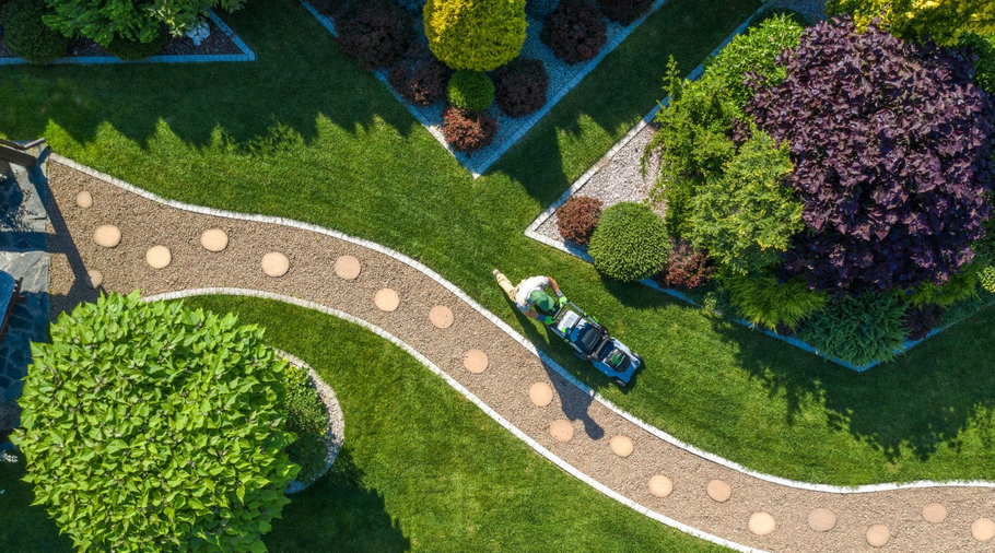 An aerial view of a person mowing the grass in a garden.
