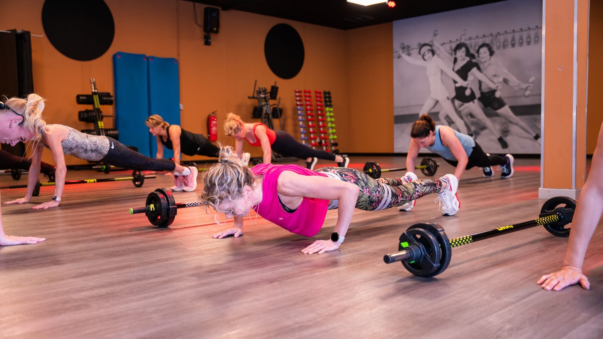 Een groep vrouwen is push-ups aan het doen in een sportschool.