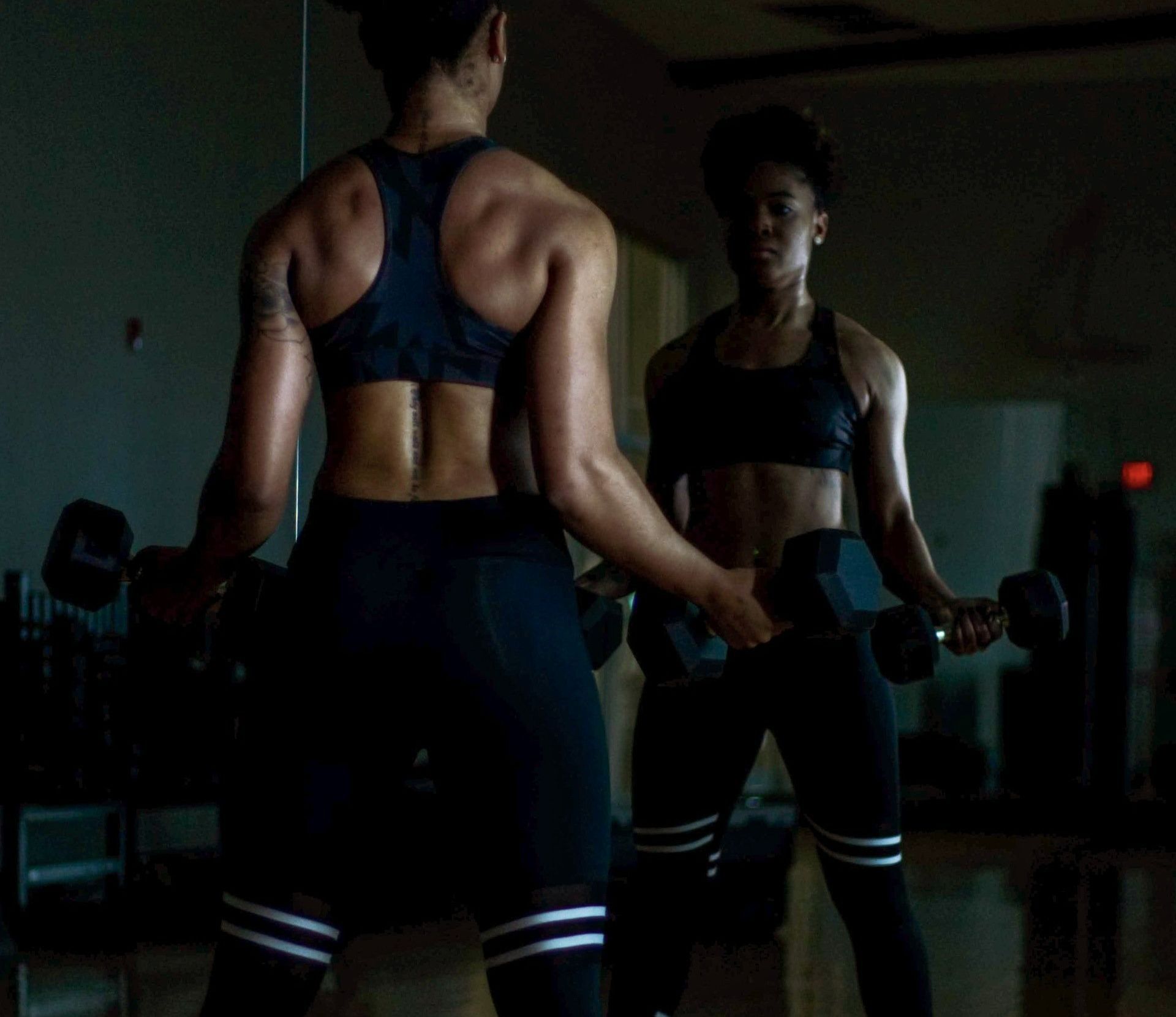 Een vrouw houdt een halter voor een spiegel in een sportschool.