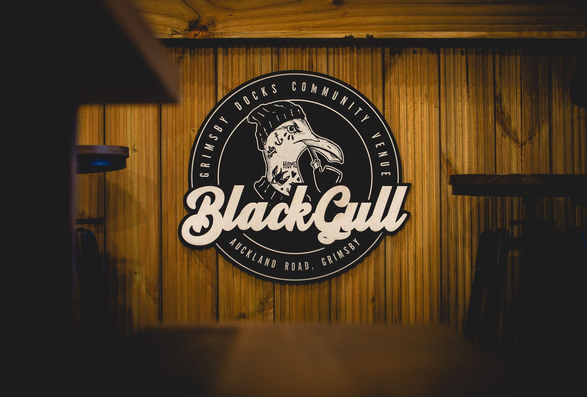 Black Gull logo on wood paneling: black circular emblem with a bird illustration, white text.