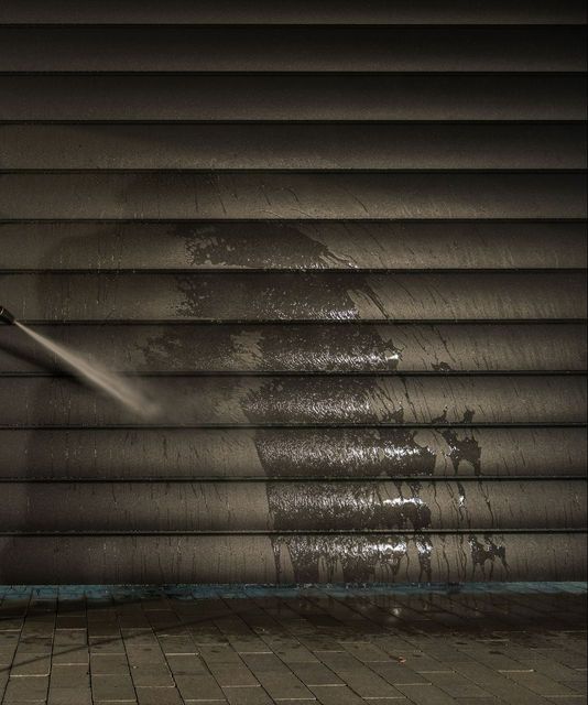 A person is cleaning a garage door with a high pressure washer.