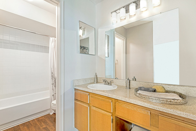 A bathroom with a sink , mirror and bathtub.