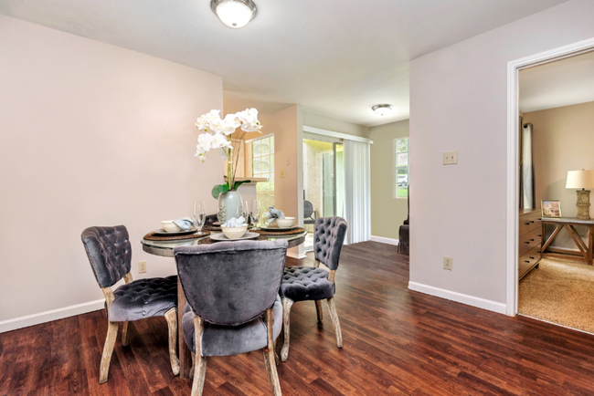 A dining room with a table and chairs and hardwood floors.