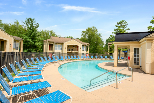 A large swimming pool surrounded by blue chairs and a building.